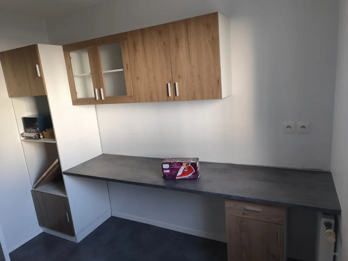 Aménagement mural sur mesure : rangements hauts dont deux éléments vitrés, plan de travail filant en bureau, colonne de rangement et caisson bas